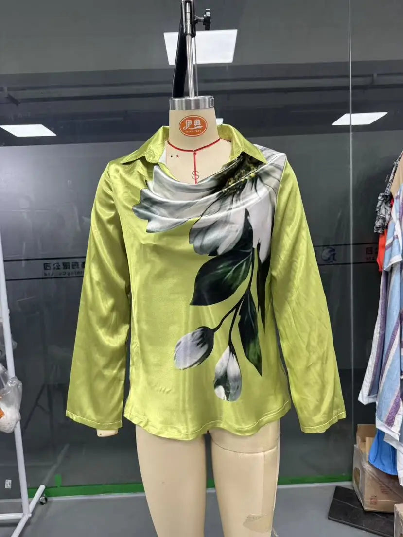 A vibrant lime green satin long sleeve blouse with a bold black and white floral print and elegant cowl neck displayed on a mannequin.