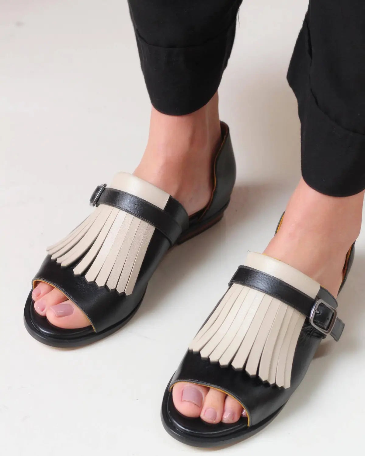 women’s tassel leather beach sandals in black and cream featuring fringe detail on black and cream leather