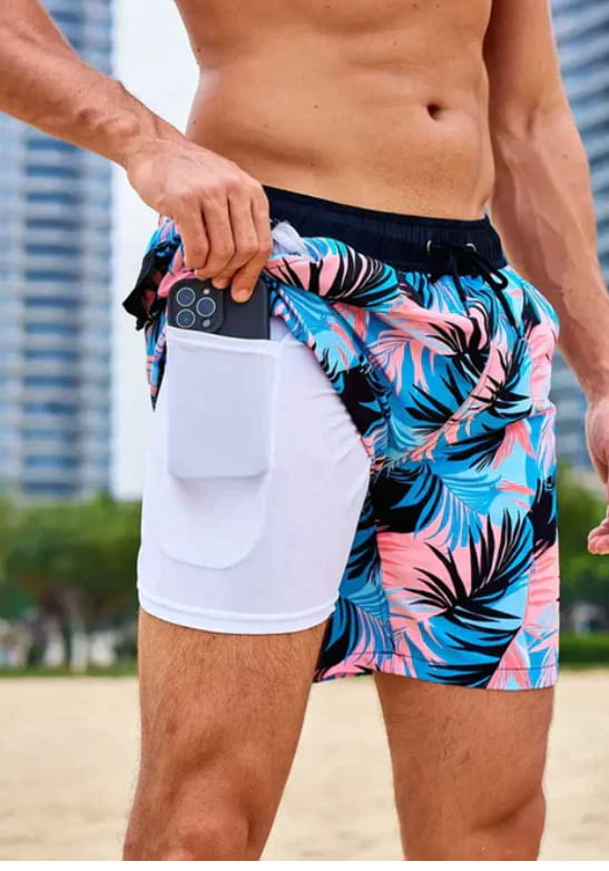 Men’s geometric print double layer beach shorts featuring a tropical leaf pattern, white inner lining, and side pocket for phone storage.