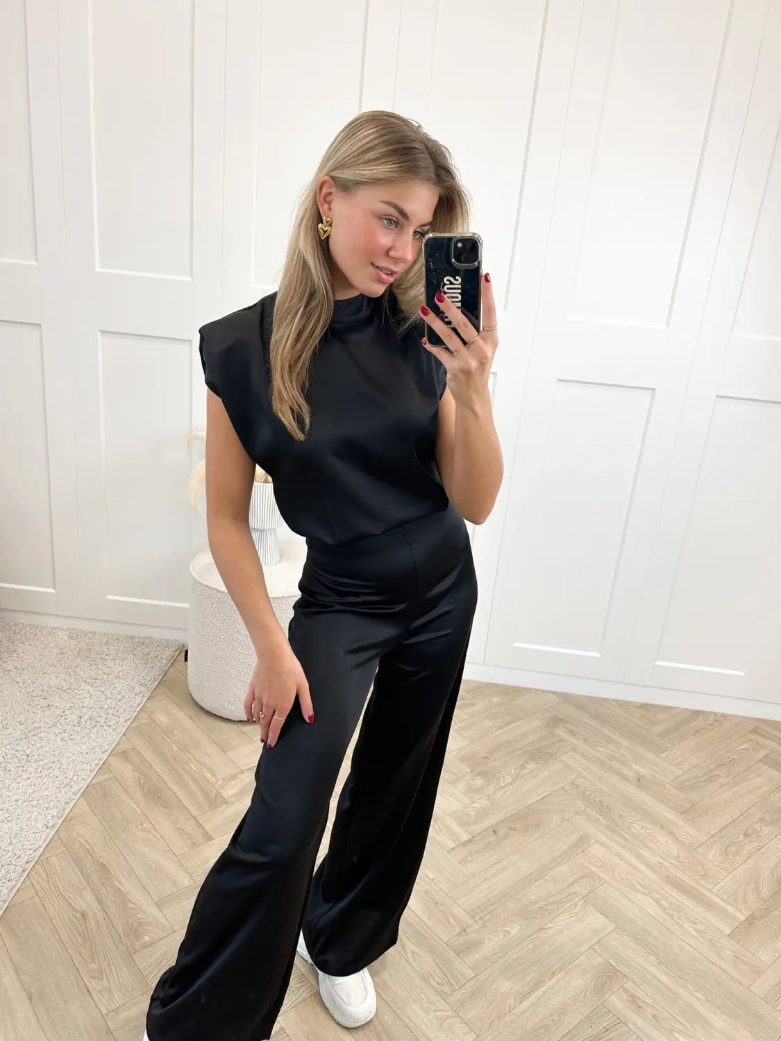 black satin sleeveless backless evening dress jumpsuit with high neckline and flowing fabric in straight pants style shown from the back.