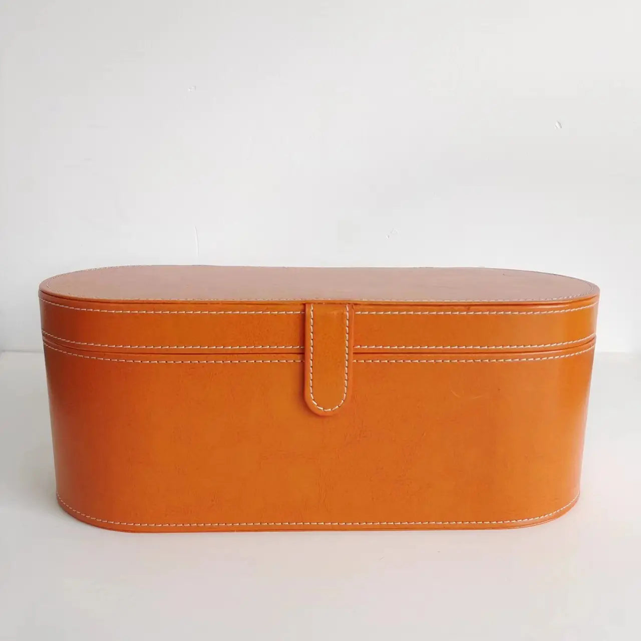 orange leather oval makeup case with white stitching and central flap closure included in 5-in-1 hot air comb hair dryer and styler set
