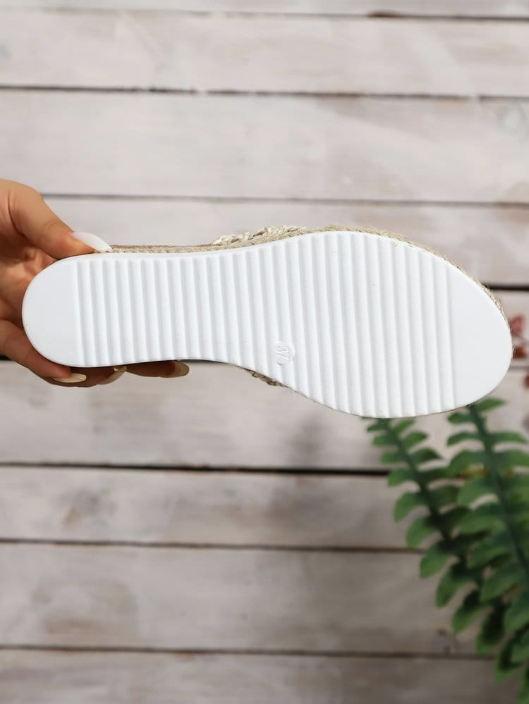 white rubber sole with vertical ridges attached to a women’s mesh espadrille platform wedge sandal featuring gold and silver embellishments