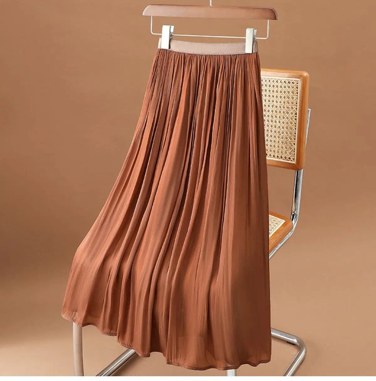 Ein fließender rostfarbener irrisierender Chiffon-Faltenrock im Midi-Format aus leichtem Gewebe.