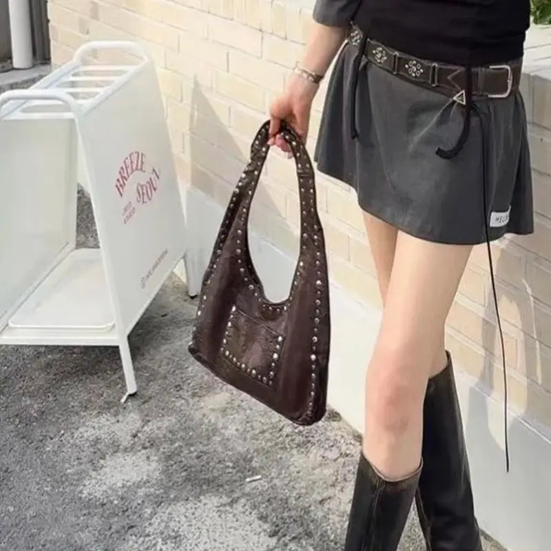 Brown leather hobo shoulder bag with silver studs along the handles and front pocket featuring a retro studded design.