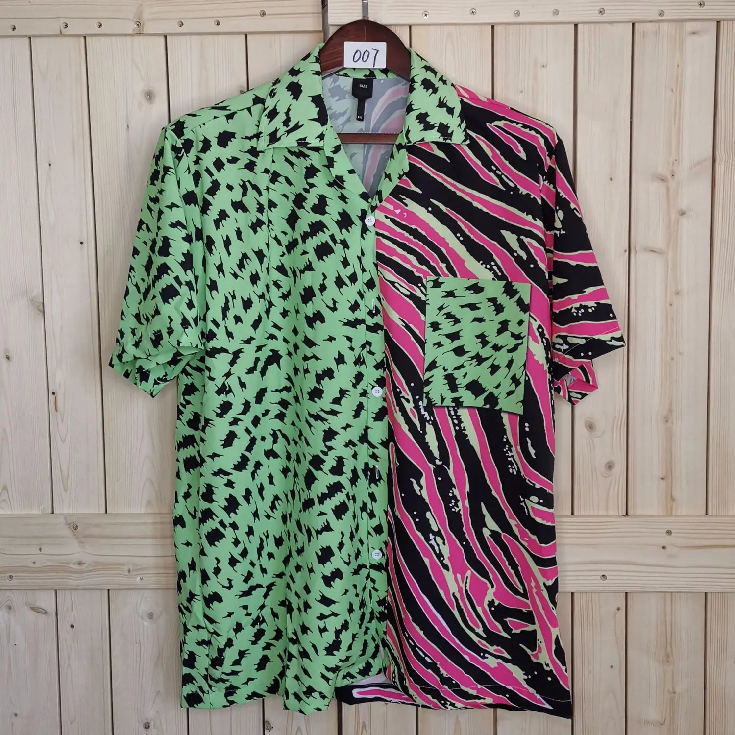 Split animal print pink and green short sleeve shirt featuring a vibrant green and black leopard print with a bold pink black and white zebra stripe pattern on the right side.