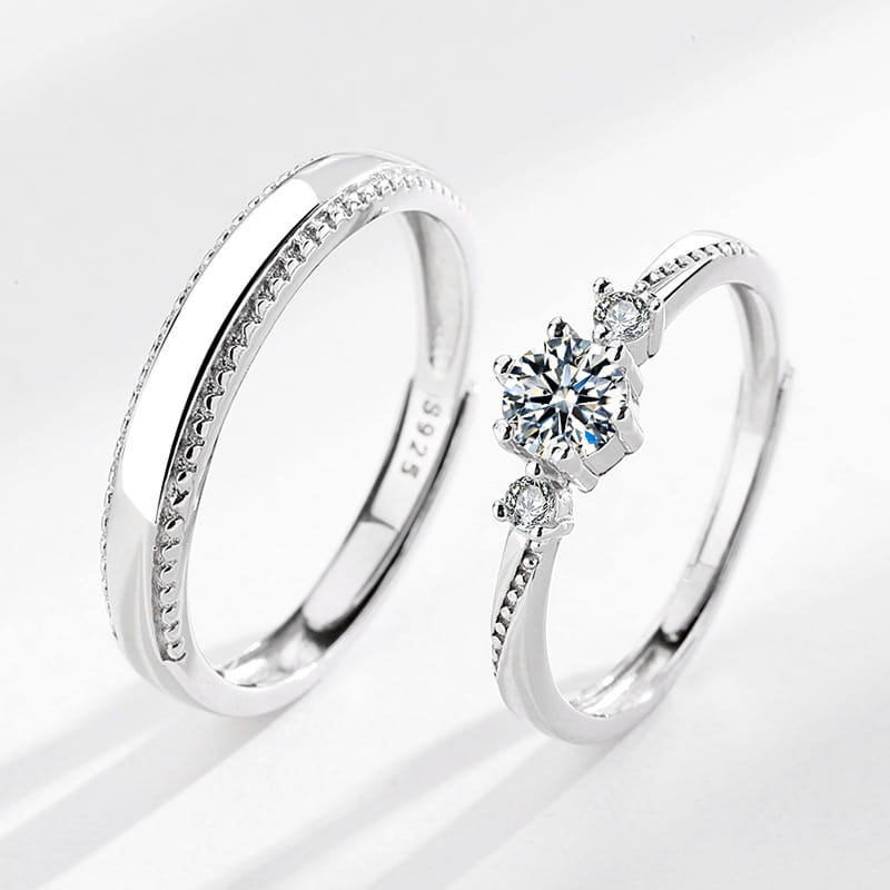 A sleek silver 925 sterling silver engagement ring with a central round-cut diamond and two smaller diamonds paired with an elegant matching band featuring a continuous line of tiny pavé-set stones from Love at First Sight Diamond Sterling Silver Couple Rings.