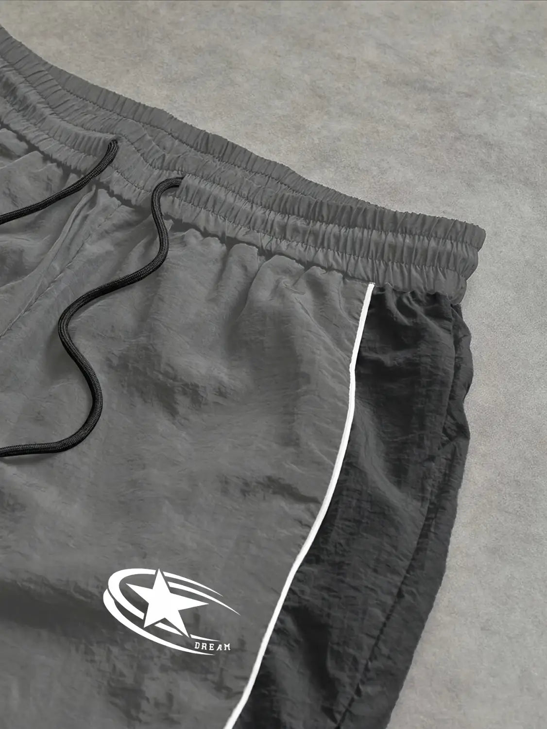 Men quick dry athletic track pants in gray featuring an elastic waistband, black drawstrings, a white star logo, and a side stripe.