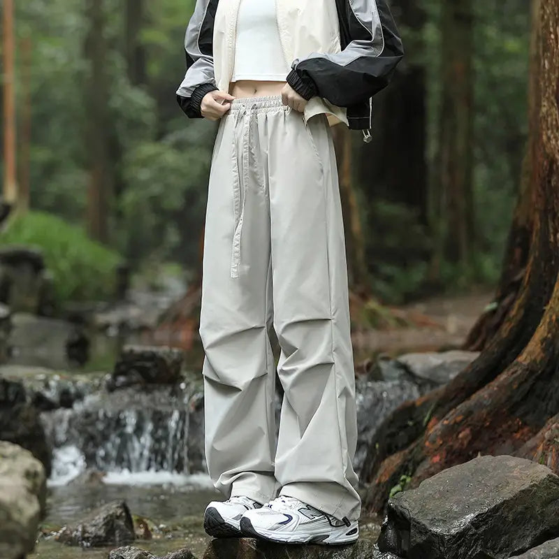 Light gray pleated cargo hiking pants for men and women featuring a loose fit and drawstring waist.