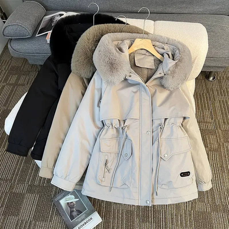 Parka matelassée à capuche avec col de fourrure beige, capuche doublée de fausse fourrure gris clair duveteuse et plusieurs poches avant.