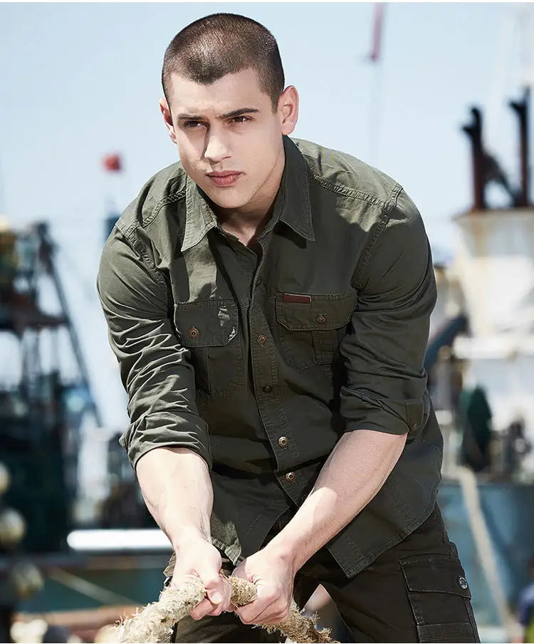 Chemise d’homme d’extérieur à manches longues boutonnée en coton vert olive, dotée de deux poches de poitrine et de manches retroussées.