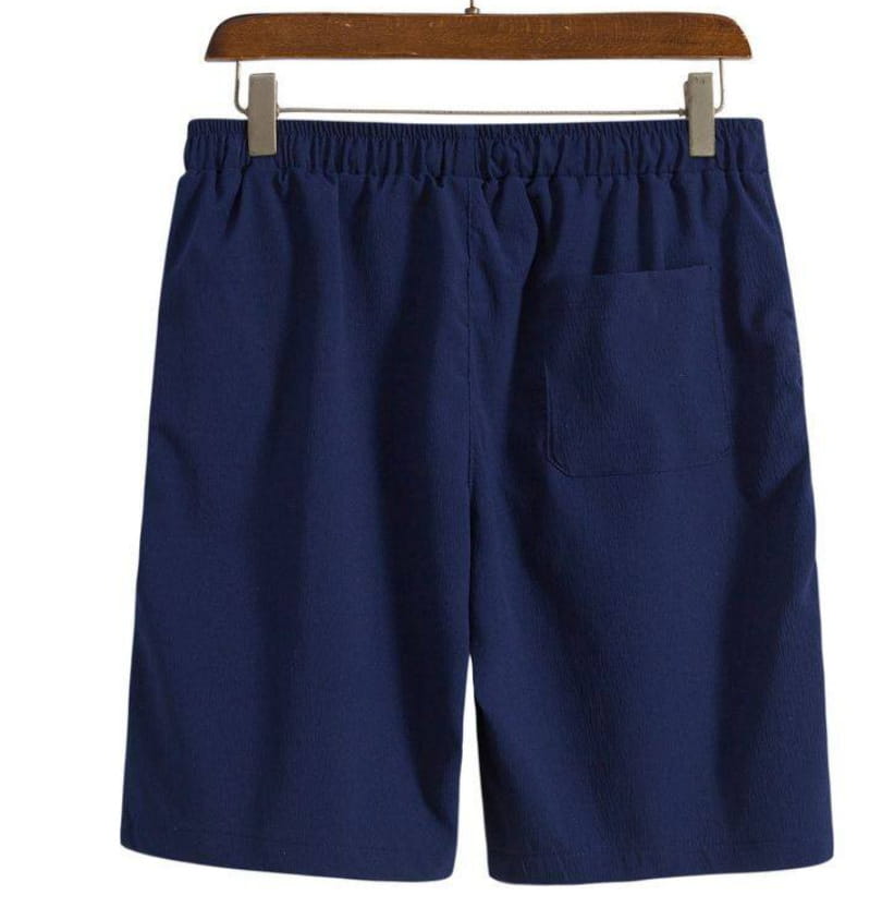 Short de plage en coton lin pour hommes beige présenté de dos, côté bleu marine en coton, avec une ceinture élastique et une poche arrière unique