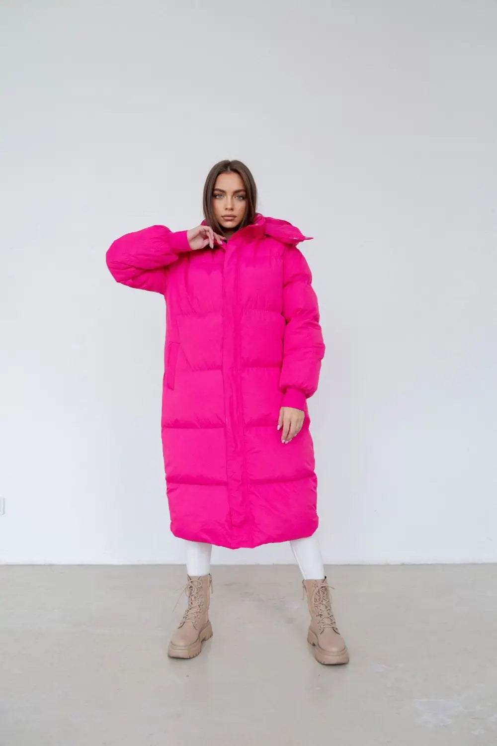 Une doudoune matelassée fuchsia pour femme, avec un design matelassé et une capuche adaptée aux vêtements d’hiver.