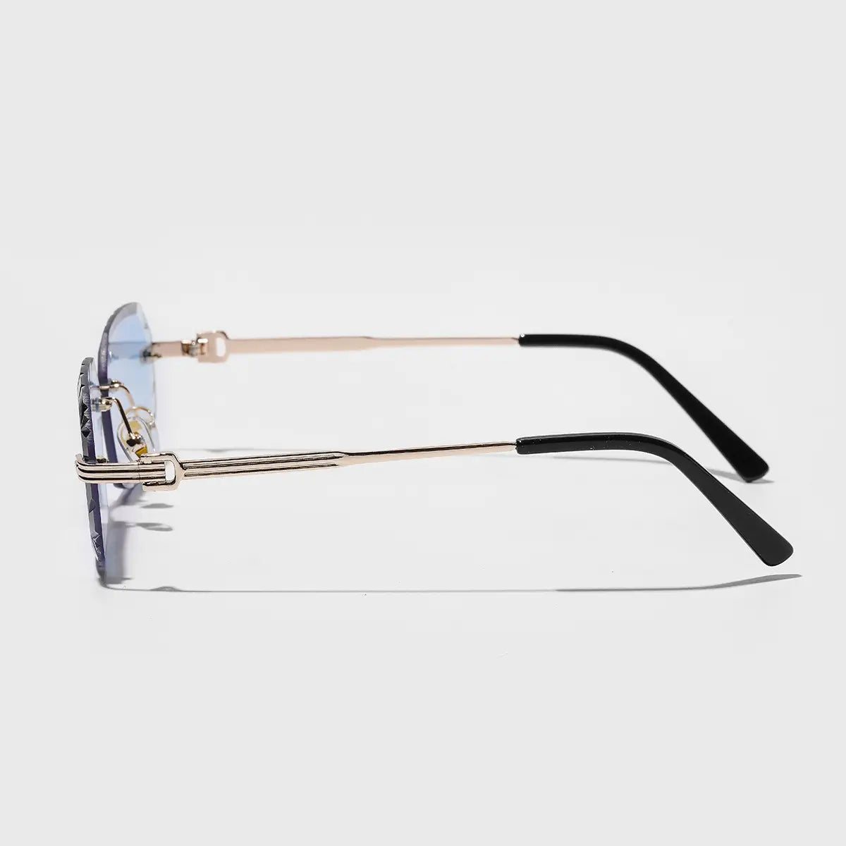 Rahmenlose geometrische Diamant-Schnitt-Gradienten-Sonnenbrille mit einer goldfarbenen Metallfassung, schwarzen Bügelspitzen und hellblauen Gradientenlinsen