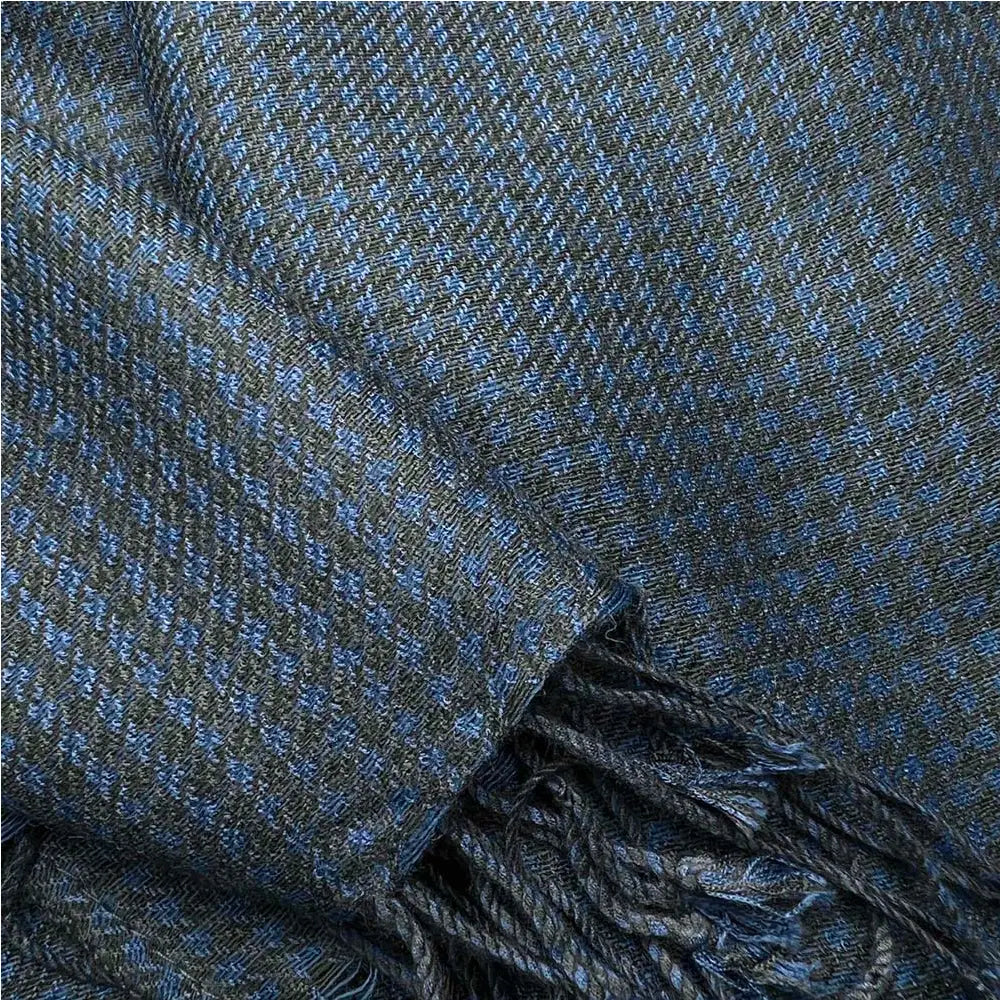 Une écharpe en sergé jacquard à chevrons marine, en laine bleu foncé et grise, aux bords frangés.