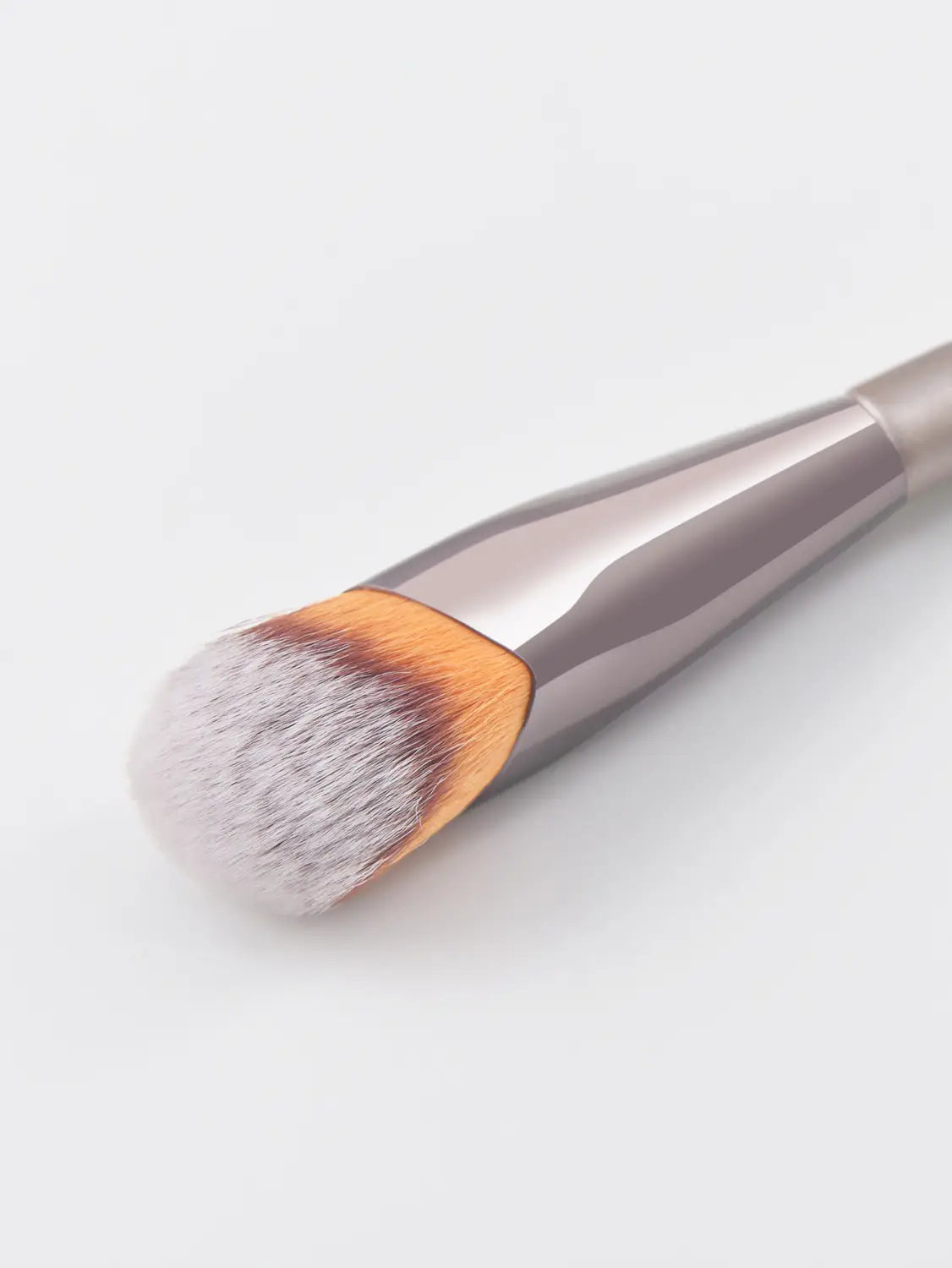 A sleek metallic-finish finger belly makeup brush with a dense rounded head of soft white and orange-tipped bristles designed for professional contouring.