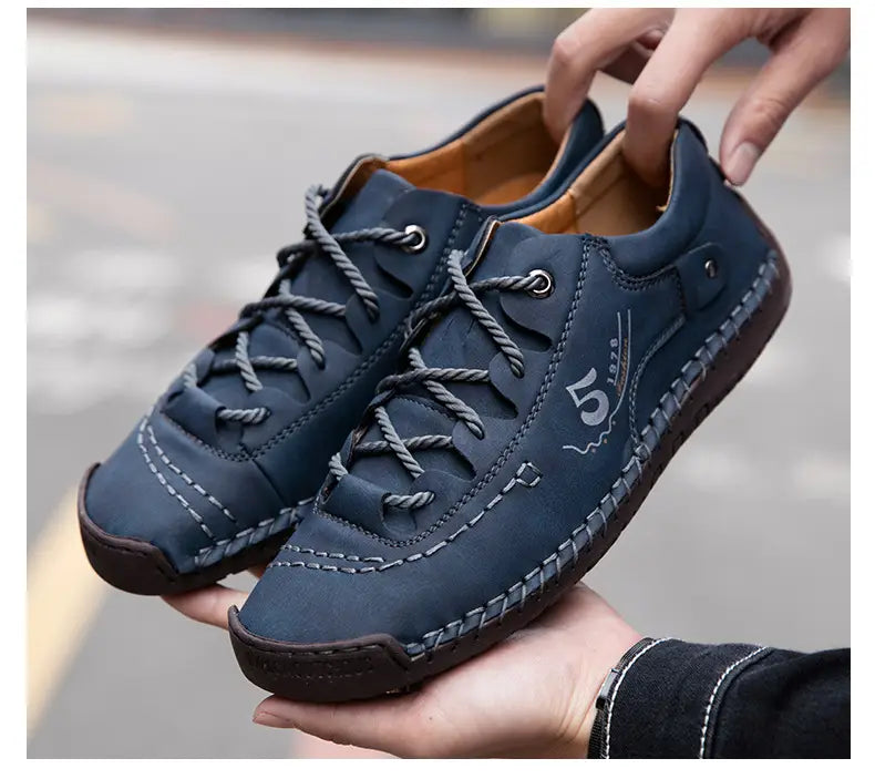 Herren-Lederschuhe im britischen Casual-Stil mit Schnürung aus dunkelblauem Leder mit grauen Kordschnürsenkeln und weißen Ziernaht-Details.