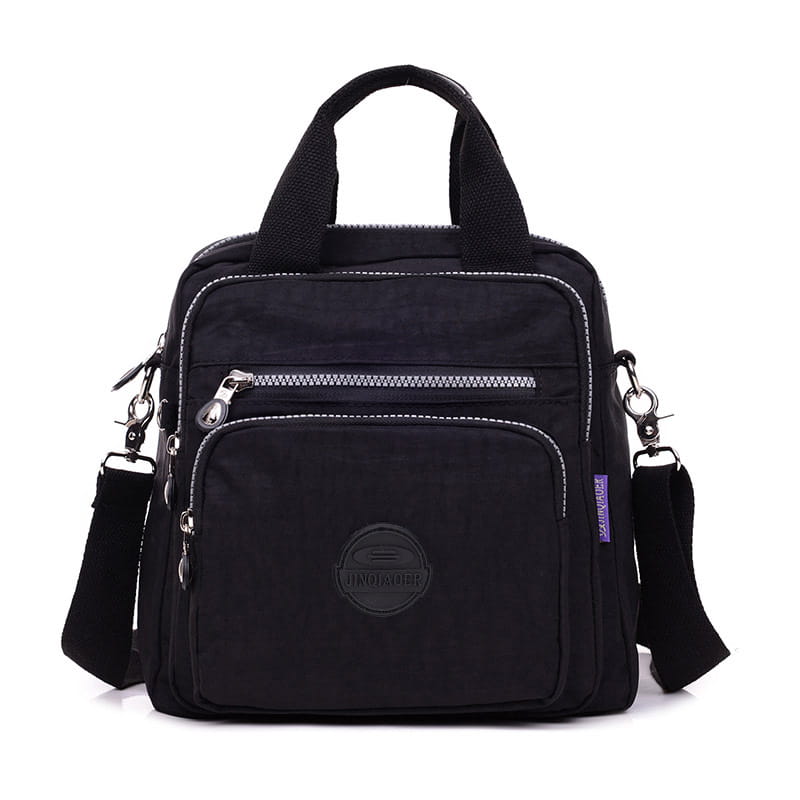 Black nylon messenger bag with multiple silver zippers, top handle, adjustable crossbody strap, and circular logo patch on the front.