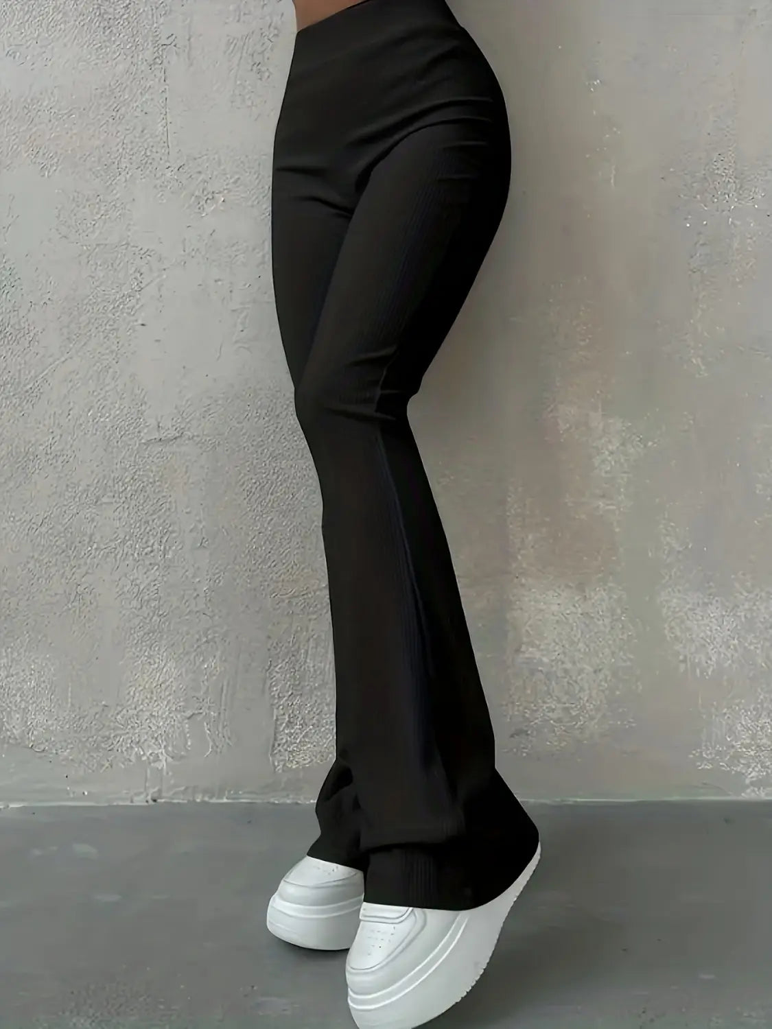 Schwarze hoch geschnittene Ripp-Flared-Leggings aus glattem, elastischem Material mit einer ausgestellten Silhouette.
