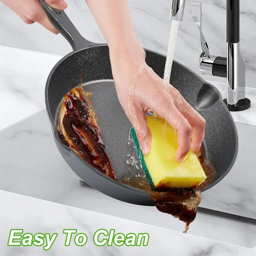 Black non-stick cast iron skillet with sturdy handle being cleaned under running water from 3-piece pre-seasoned set