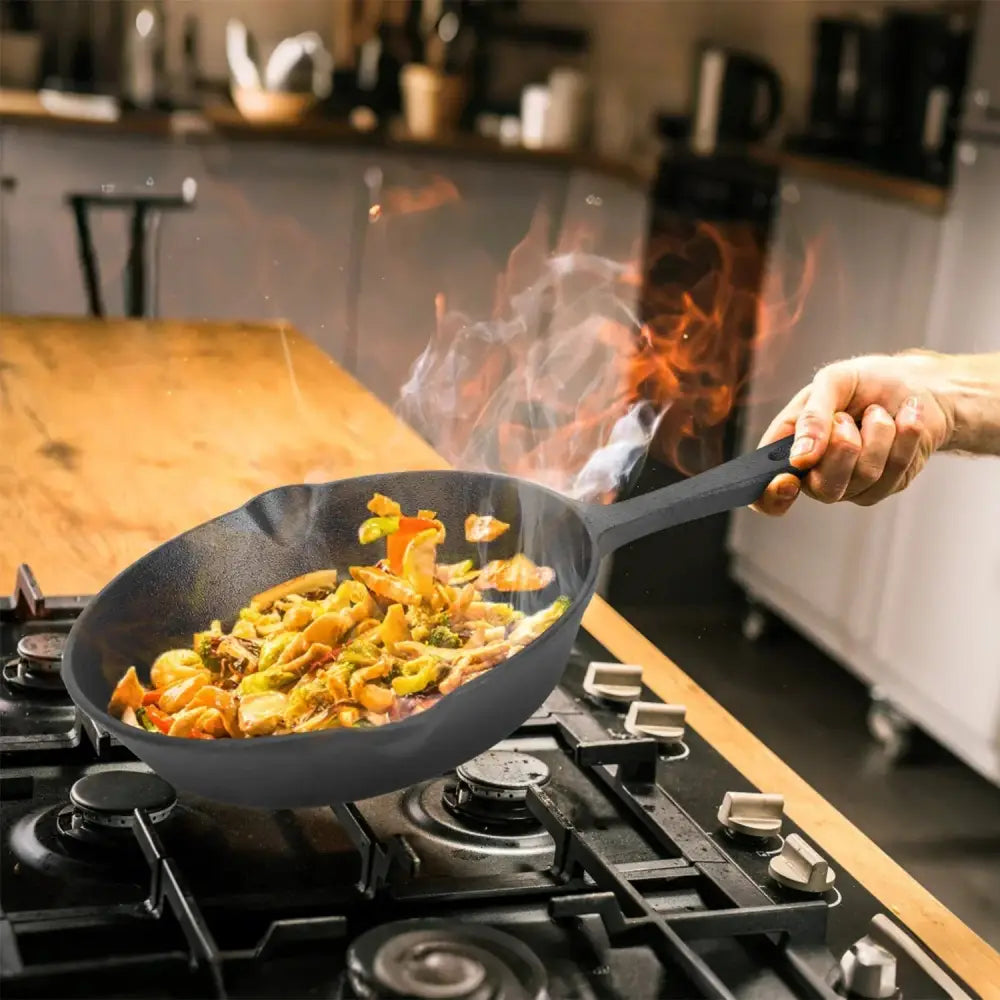 Black non-stick cast iron skillet from 3-piece pre-seasoned set with food sizzling and flames rising inside