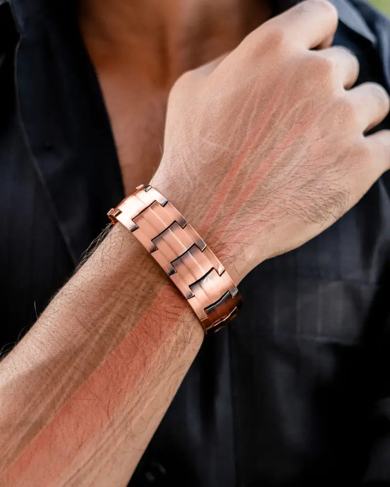 A sleek rose gold pure copper magnetic bracelet with a modern interlocking link design worn on a man’s wrist