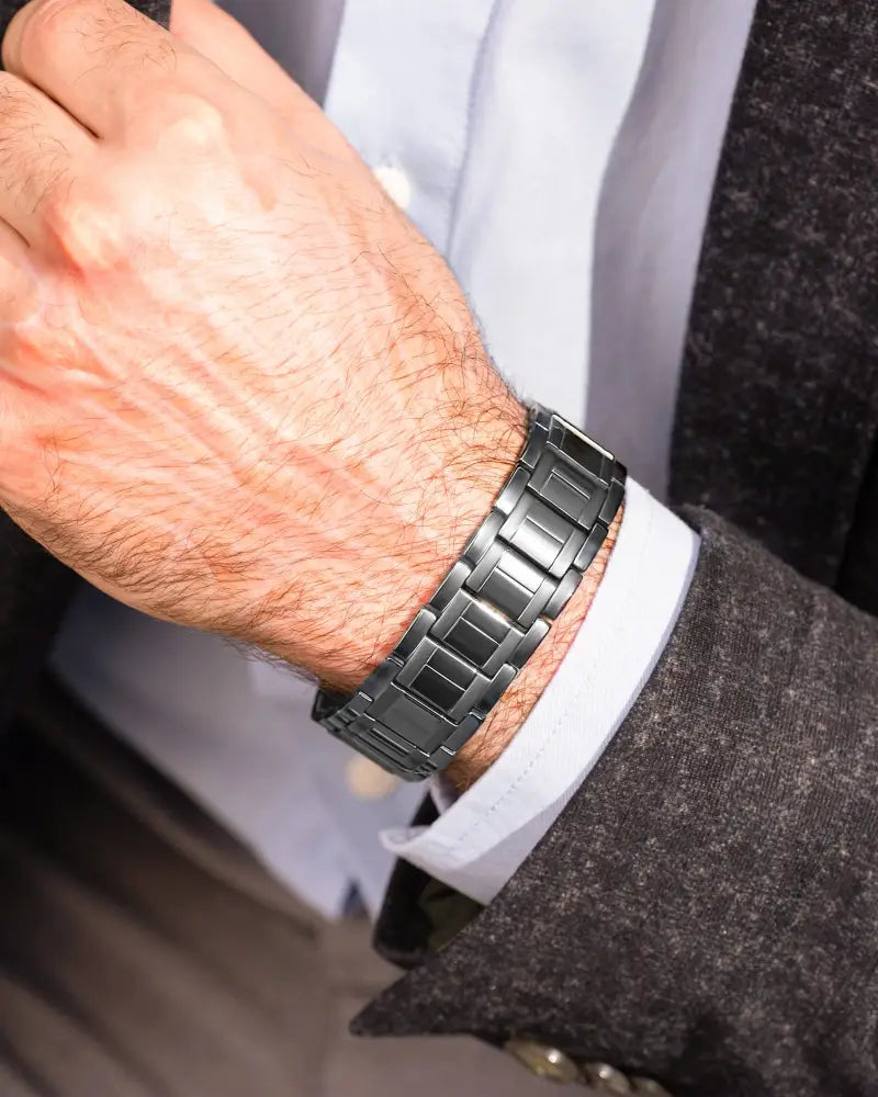 A sleek dark gray metallic watch band with a modern interlocking link design in a magnetic therapy bracelet