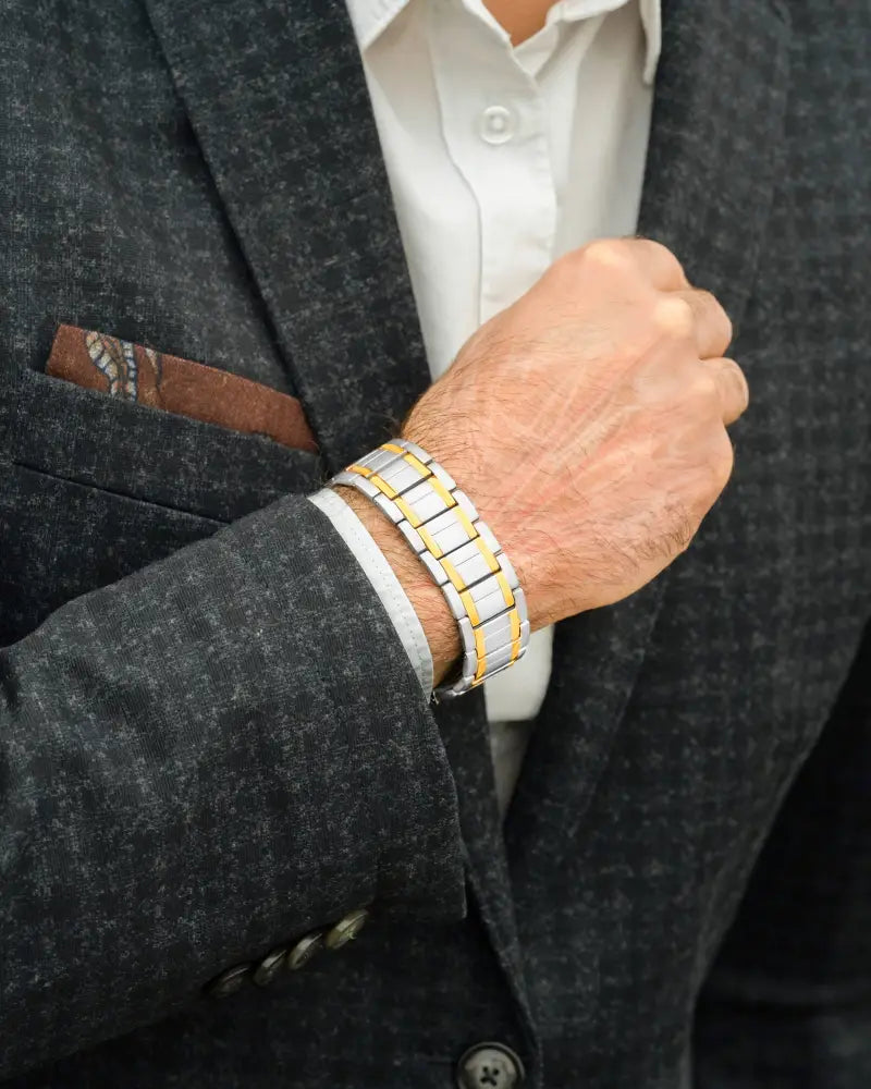 Two tone titanium magnetic therapy bracelet for men with alternating silver and gold metal links on a man’s wrist