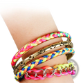 A stack of four neon pink and yellow braided bangles with gold star accents and metallic details