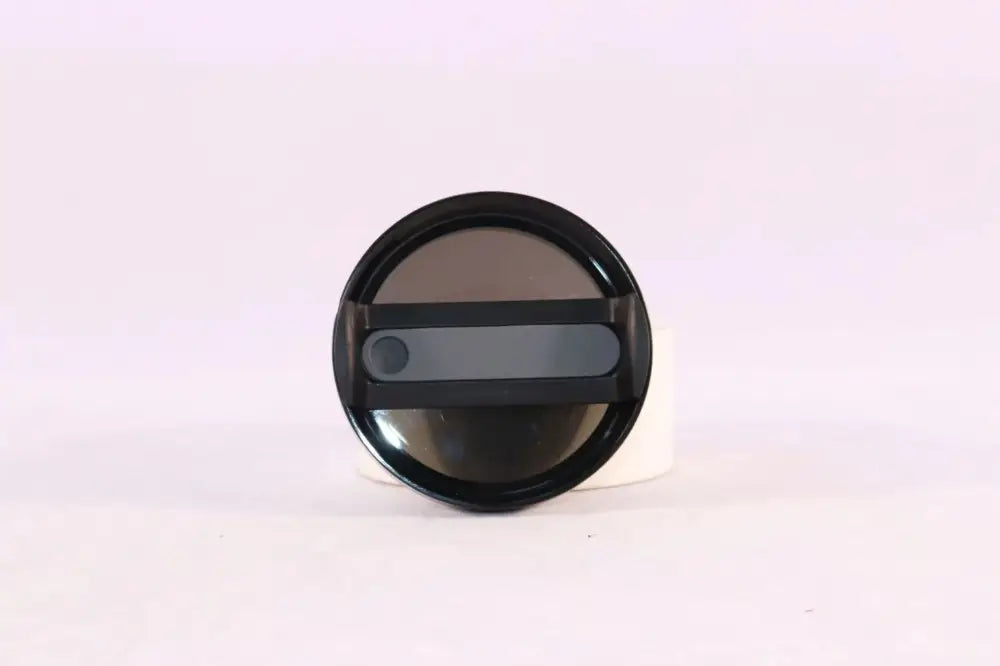 Black circular camera lens cap with gray slider and matte finish shown with arbaglobal 40 oz insulated tumbler handle and straw