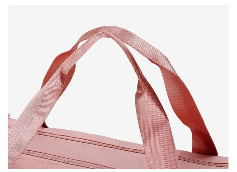 Pink woven fabric handles on a matching pink waterproof Oxford travel duffel bag designed for gym and sports use.