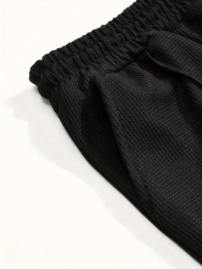 Black textured knit pants with an elastic waistband from the mens minimalist solid color sweatshirt jogger set.