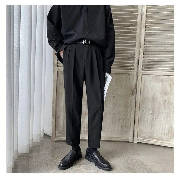Men loose fit straight leg suit pants in black pleated fabric with a tailored fit and subtle texture.