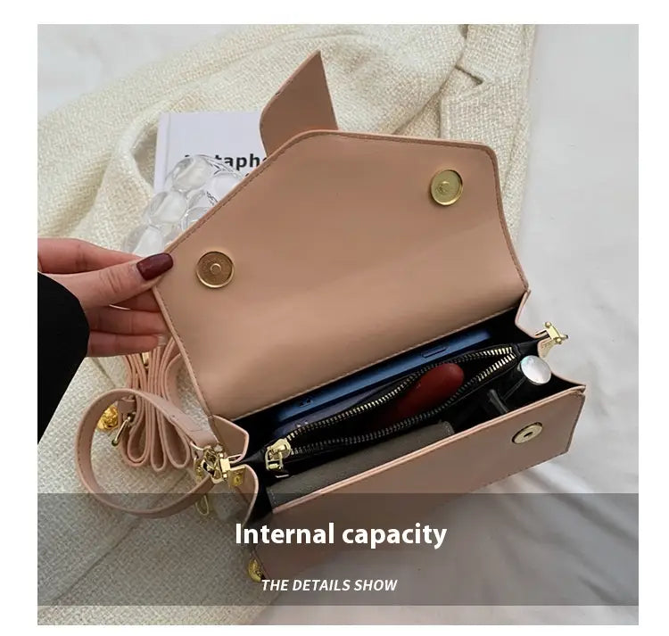 A blush pink faux leather monogram letter print crossbody messenger bag with gold tone hardware and a detachable strap.