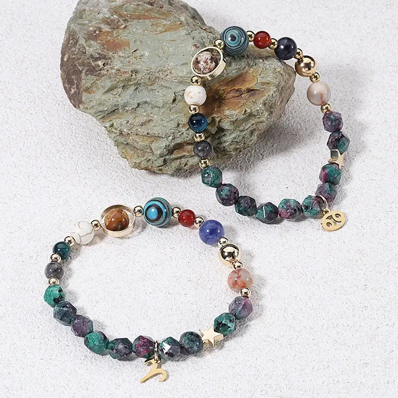 A natural stone zodiac constellation beaded bracelet featuring colorful green blue purple and red gemstones with gold-toned metal accents and charms.