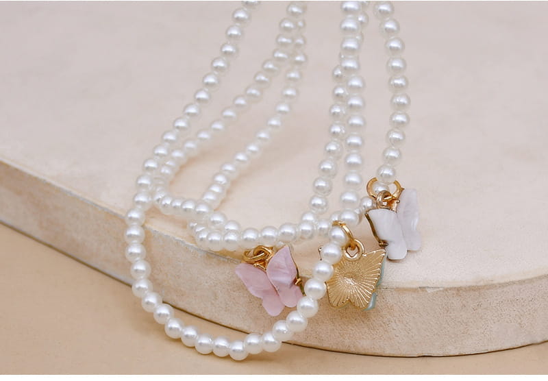 Elegant pearl butterfly charm choker necklace featuring a delicate white pearl strand adorned with soft pink and gold butterfly charms.
