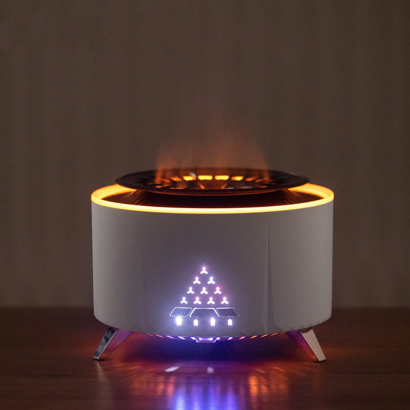 White cylindrical indoor fireplace white noise flame aroma diffuser bluetooth humidifier with glowing orange flame and led lights in a triangular pattern on the front.