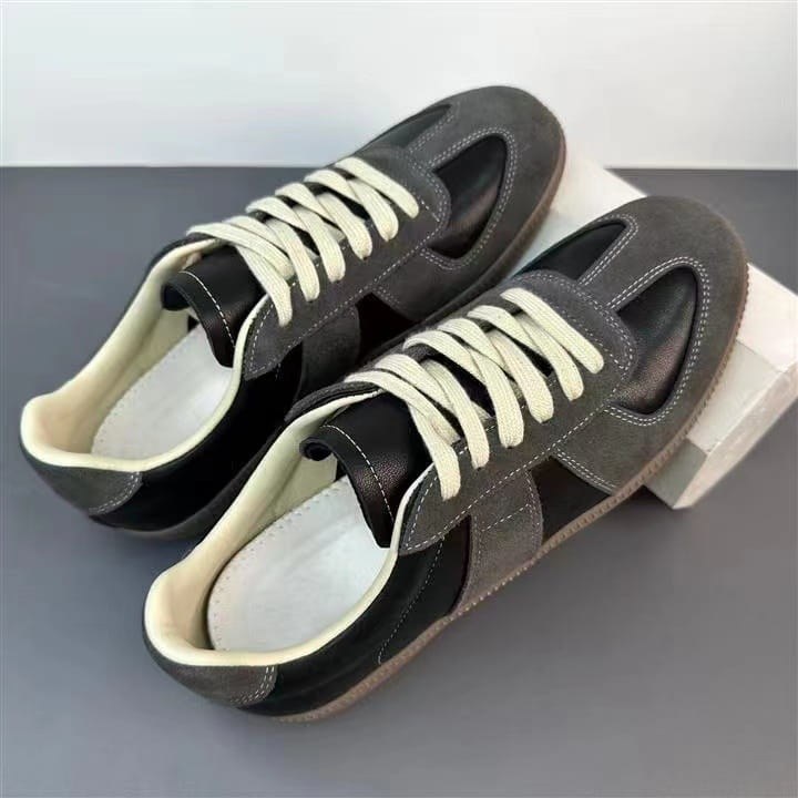 Ledersneaker, vielseitige Freizeitschuhe im Low-Top-Design, mit dunklem grauem und schwarzem Veloursleder sowie cremefarbenen Schnürsenkeln.