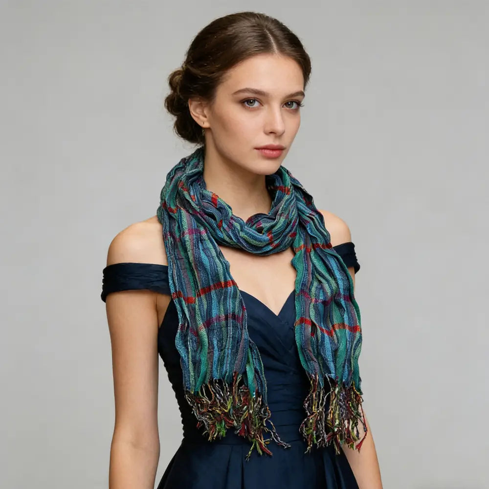 Une écharpe d’hiver bleu à jacquard texturé, avec un motif écossais turquoise et rouge multicolore et des extrémités à franges.