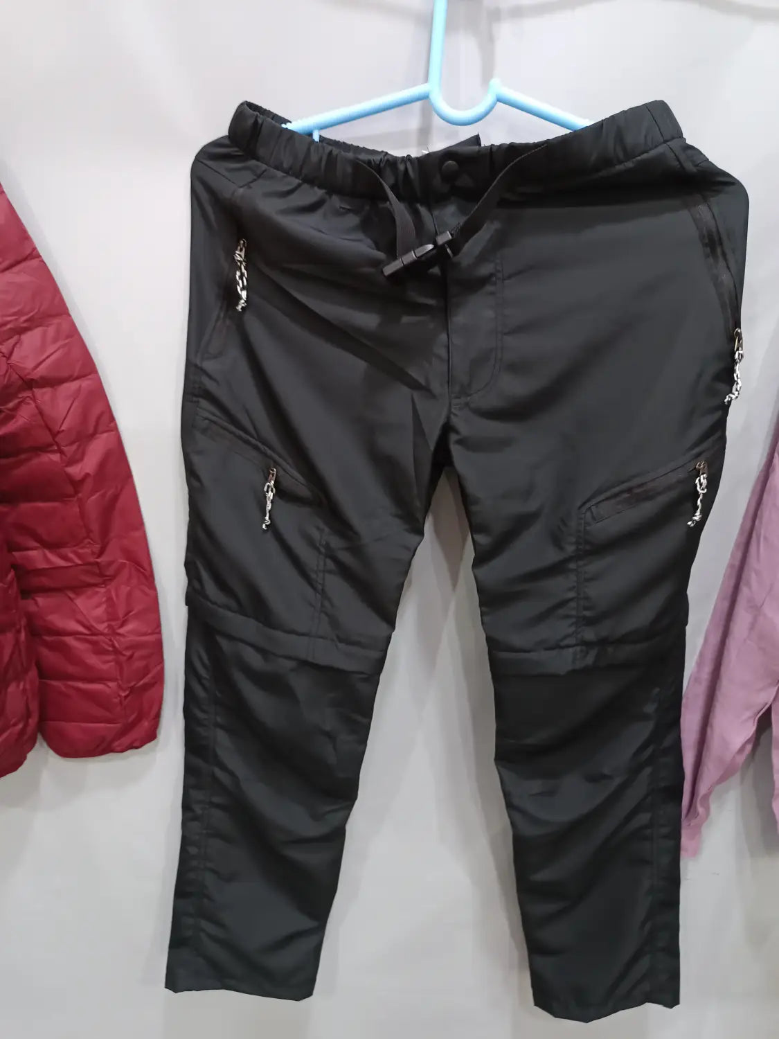 Black convertible tactical hiking pants featuring an elastic waistband and silver chain zipper pulls on multiple pockets.
