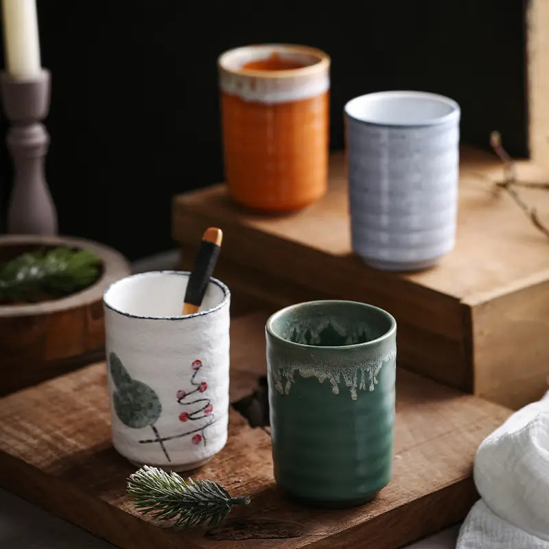Handcrafted Japanese ceramic mugs in earthy tones with rustic glazes and hand-painted botanical designs perfect for tea drinking 250ml capacity.