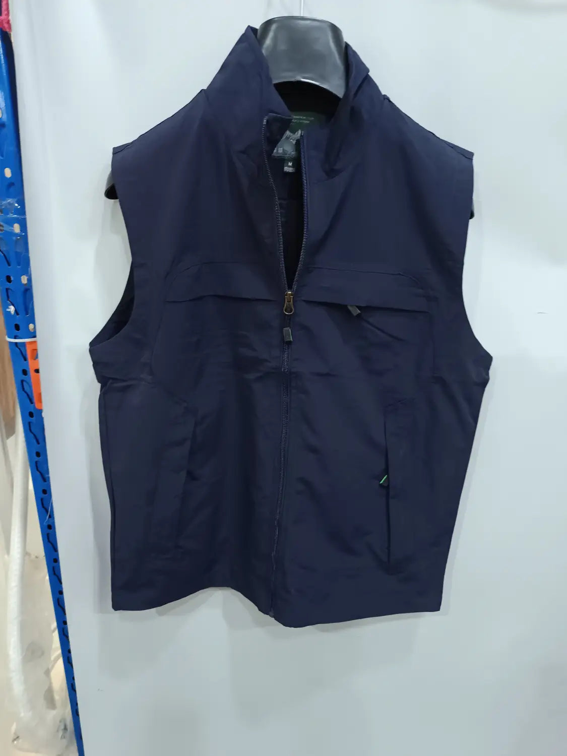 Chaleco utilitario impermeable sin mangas de color azul marino oscuro con cremallera frontal y múltiples bolsillos, diseñado para un uso funcional en actividades al aire libre.