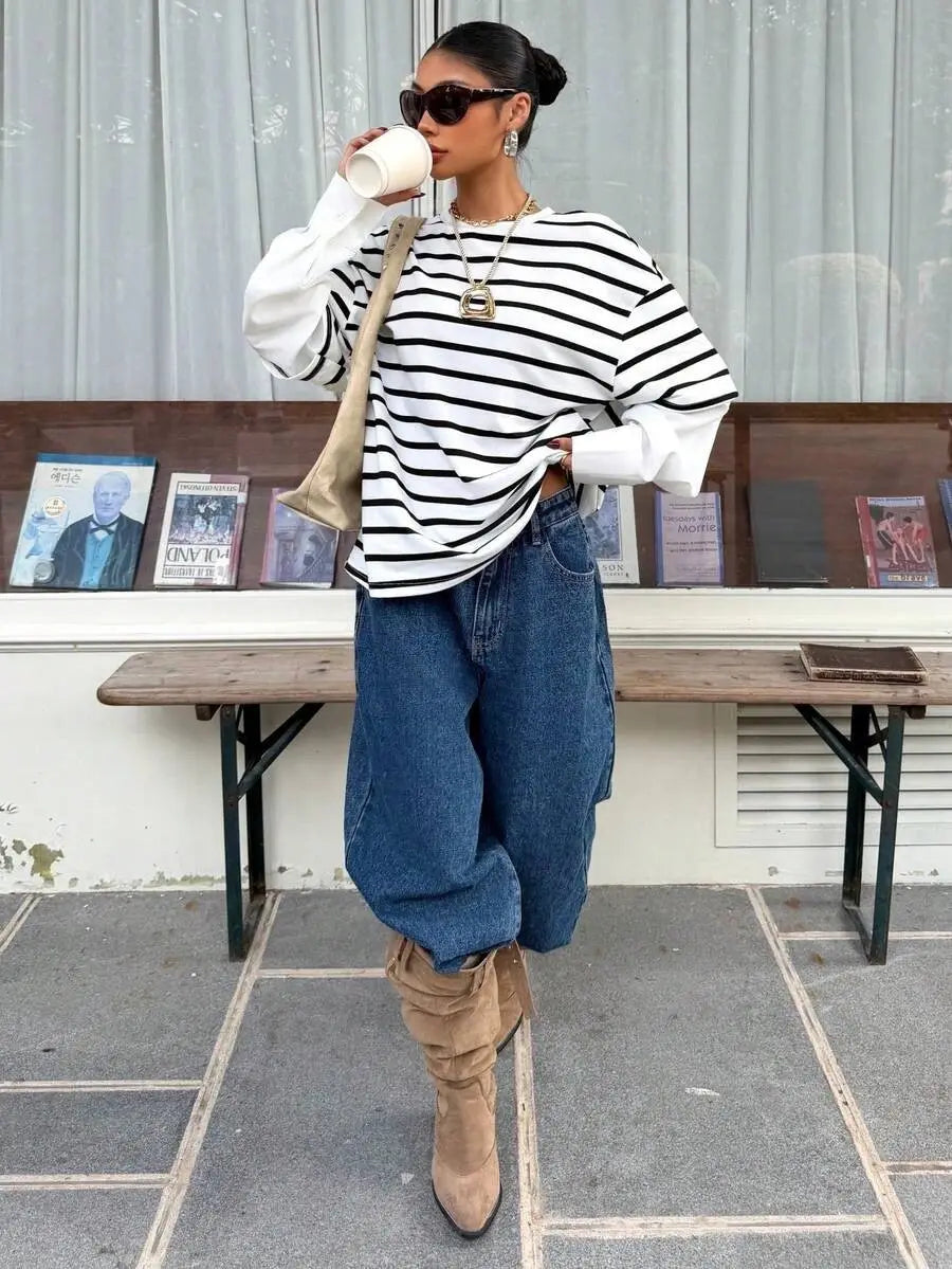 Una mujer que lleva una sudadera oversize con rayas negro y blanco tipo conjunto falso de dos piezas con mangas largas amplias y sueltas.