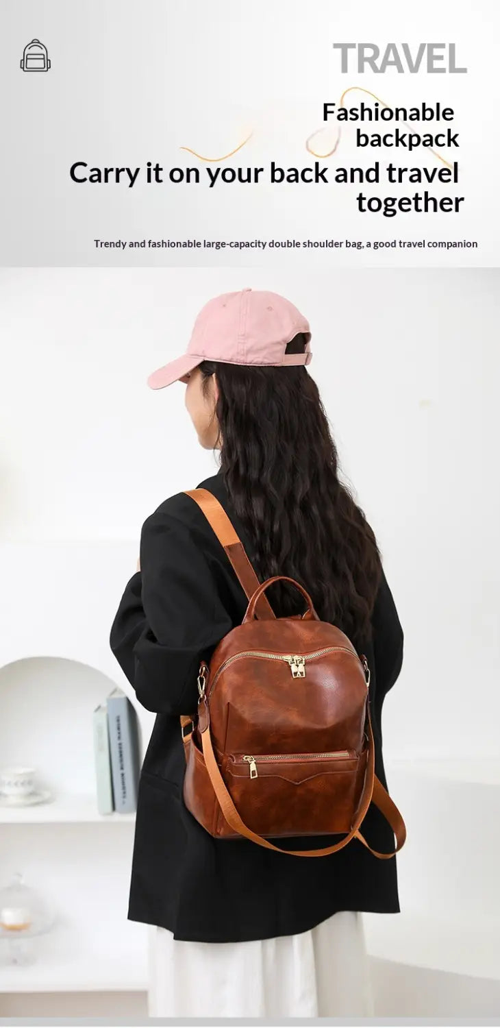 Brown leather faux leather women’s large capacity commuter backpack with double shoulder straps, zipped compartments, and a top handle.