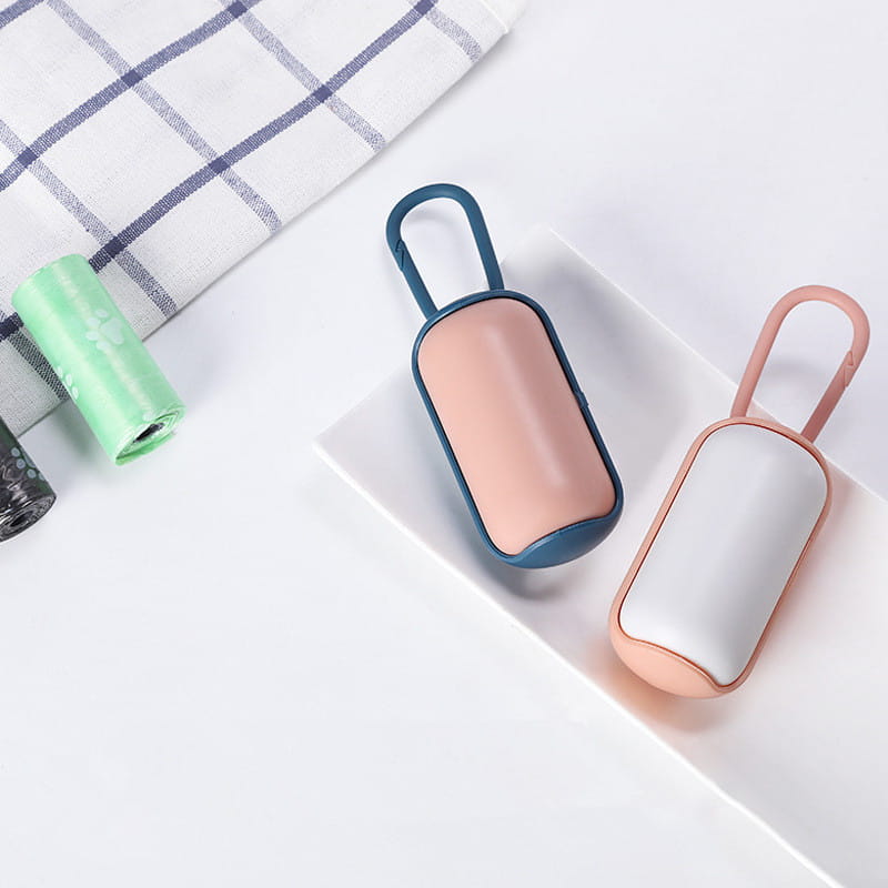 two compact rectangular pet poop bag dispensers with rounded edges and carabiner clips featuring one soft pink with teal frame and one white with blush pink frame for convenient pet waste disposal