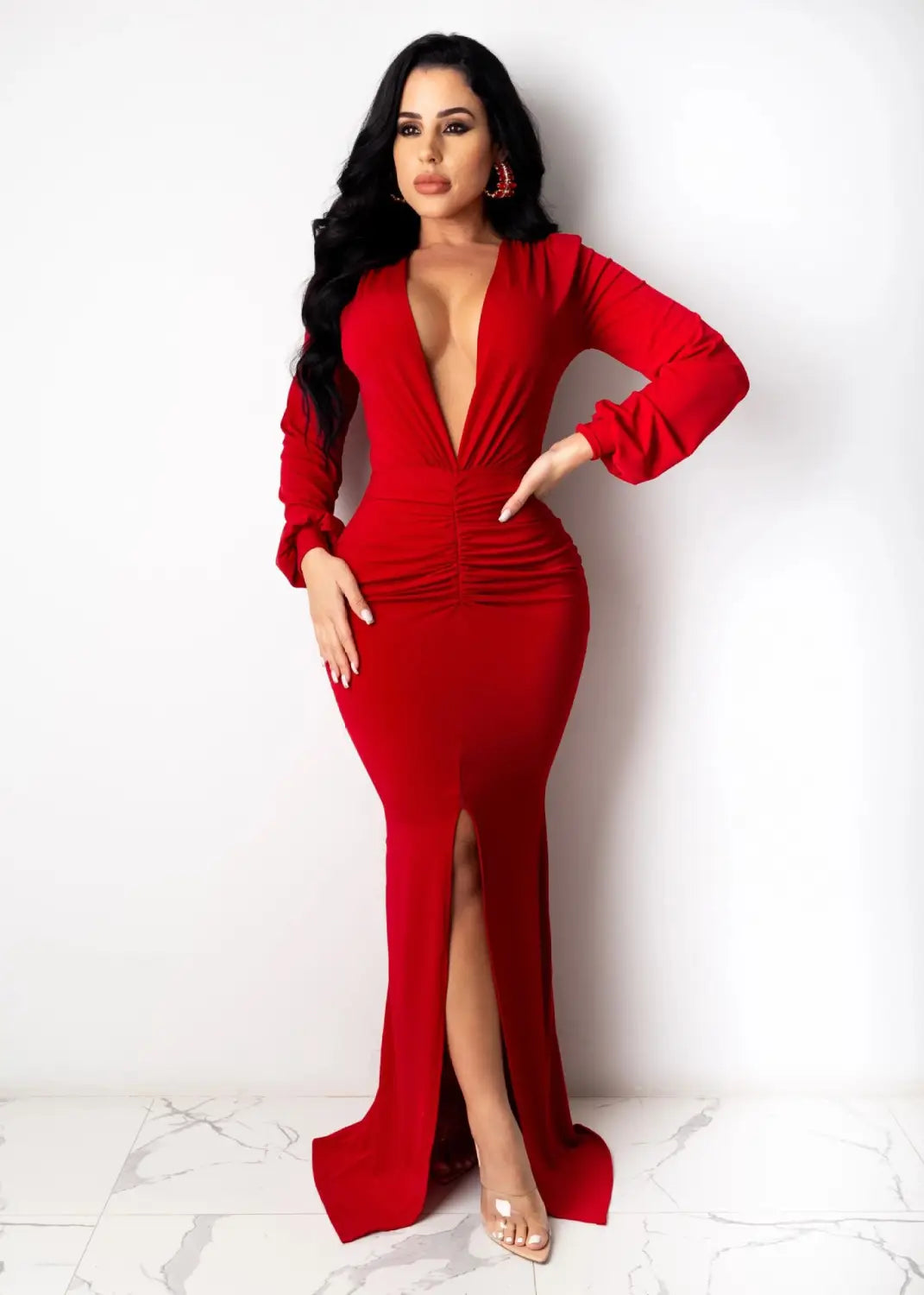 A striking red velvet v-neck evening dress with long sleeves, a plunging neckline, and a high slit.