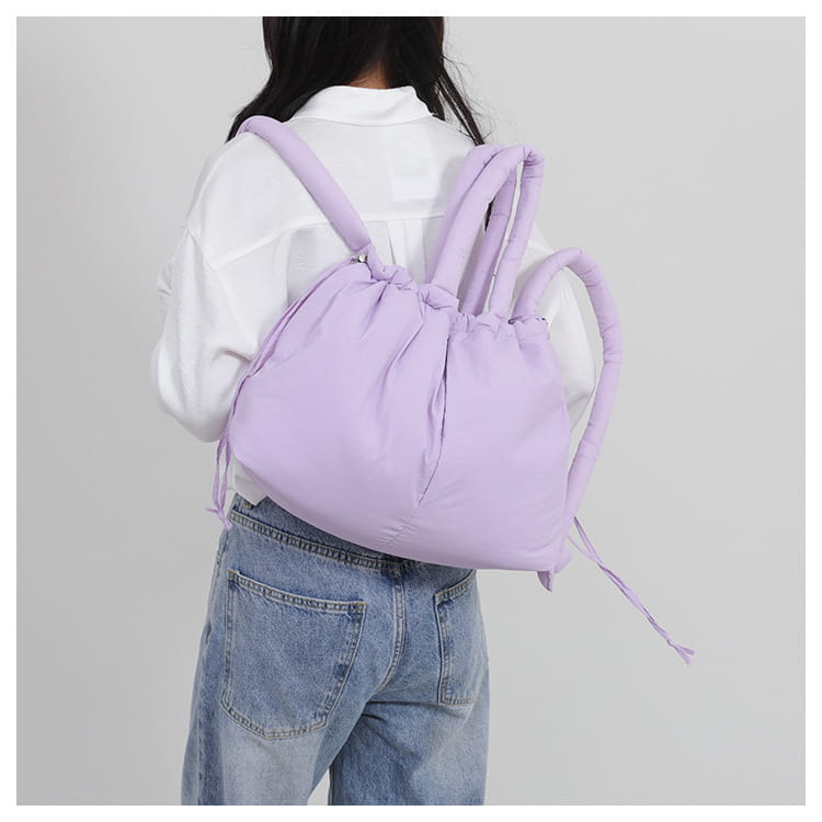 A soft lavender-colored quilted puffer tote bag made of lightweight nylon with padded shoulder straps and a drawstring closure.