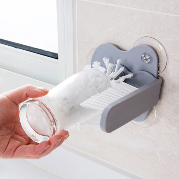 gray plastic wall-mounted glass cleaning brush holder with suction cups and white bristles for sink scrubber use