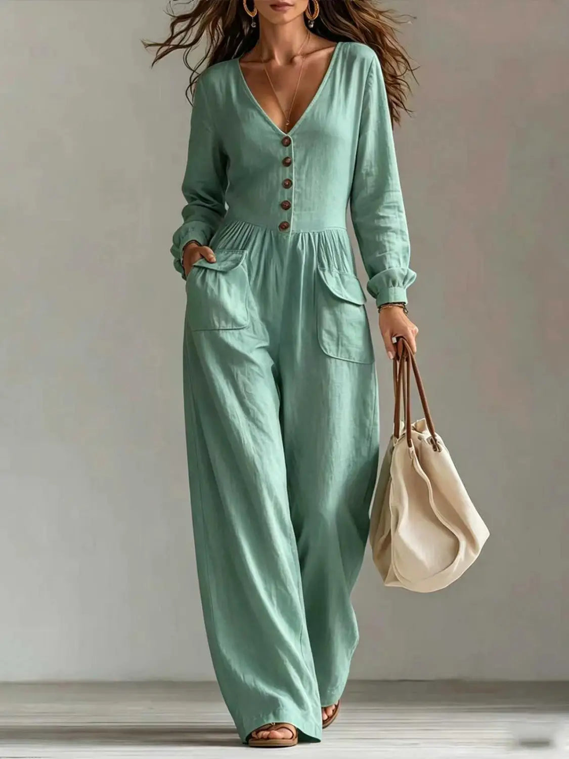 Une combinaison pour femmes vert menthe clair à décolleté en V, manches longues et jambes larges, en tissu léger, avec fermeture boutonnée.