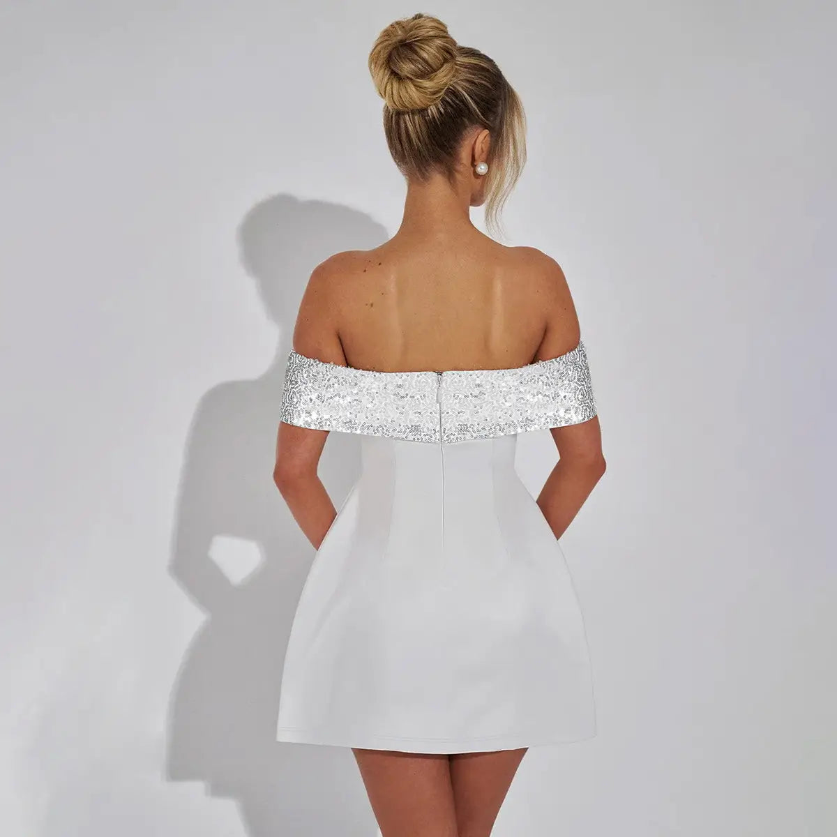 white off-the-shoulder bodycon mini dress featuring a sparkling silver sequined band across the shoulders for an elegant evening look