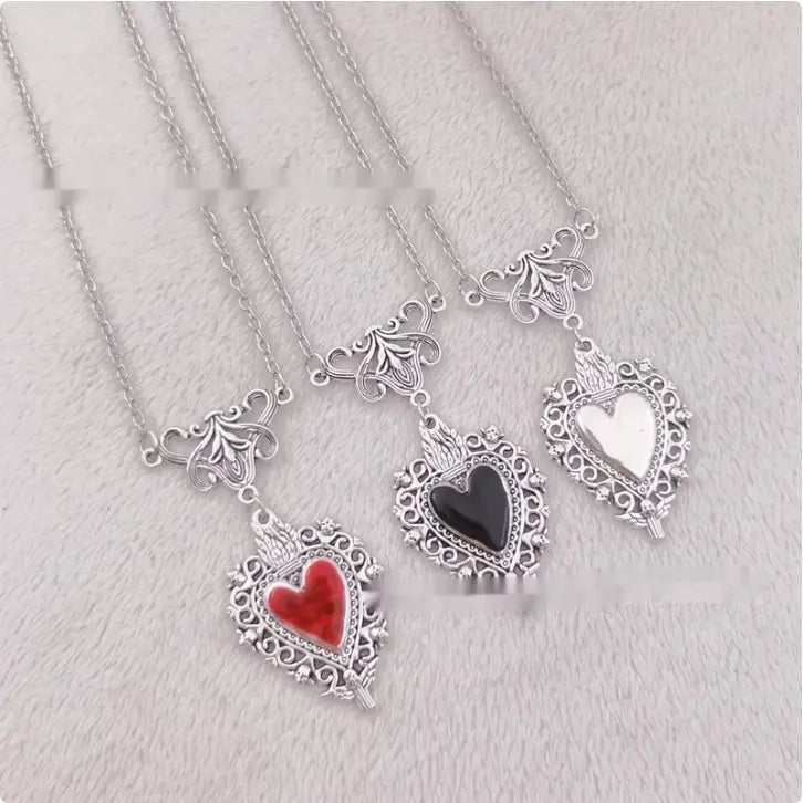 silver heart-shaped pendants with intricate filigree designs and red and black resin hearts set in ornate silver frames vintage silver filigree heart pendant with red enamel center
